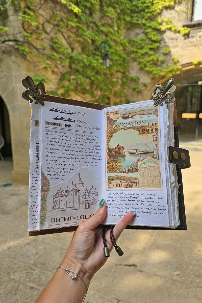 Open leather travel journal showing handwritten notes and vintage postcard collage, held outdoors